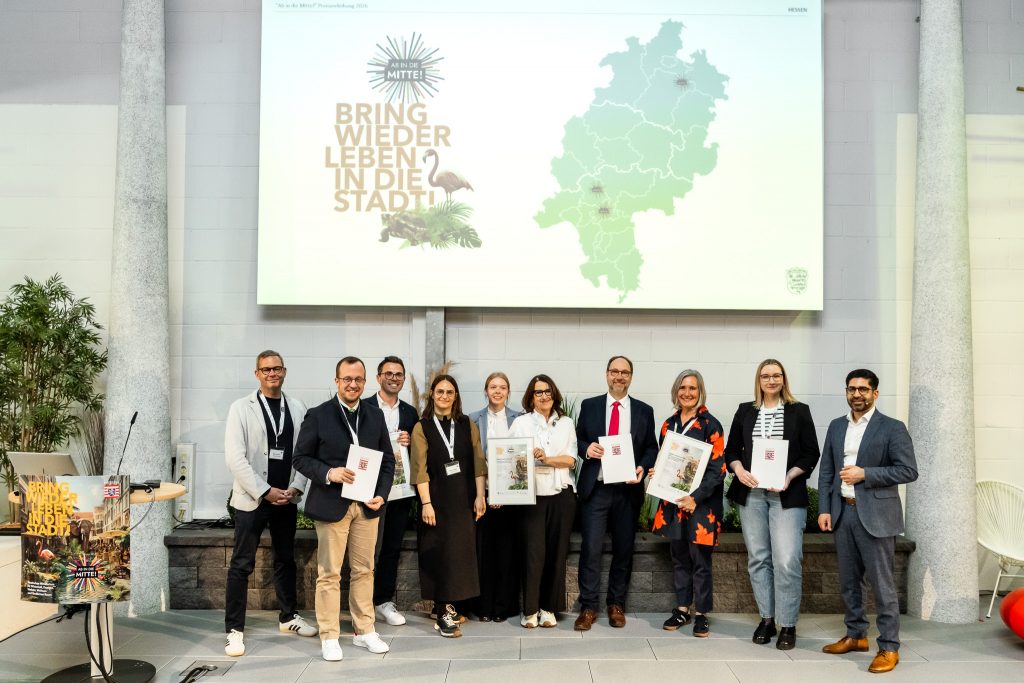 Gemeinsam auf der Bühne: Die Preisträgerstädte Frankfurt, Friedrichsdorf und Melsungen mit Staatsminister Kaweh Mansoori bei der feierlichen Preisverleihung von „Ab in die Mitte! 2026“.Foto: Cornelius Pfannkuch