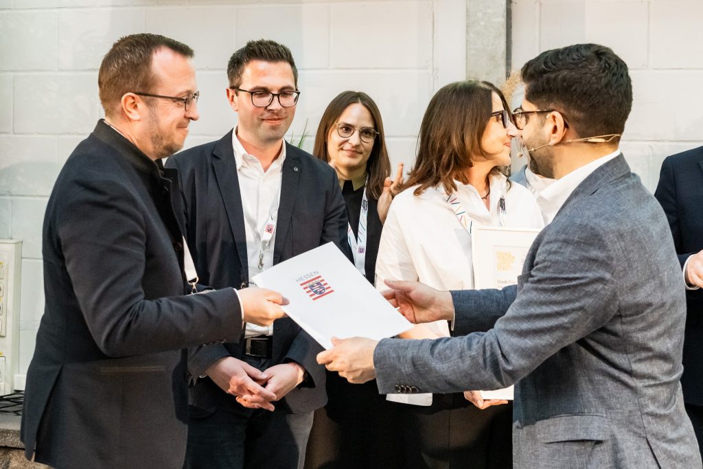 Bürgermeister Timo Riedemann und Alexander Dupont (Teamleiter Stadtentwicklung und Stadtmarketing) nehmen den Förderbescheid von Staatsminister Kaweh Mansoori für das Projekt „Treffpunkt Melsungen – Herzensprojekte“ entgegen.Foto: Cornelius Pfannkuch