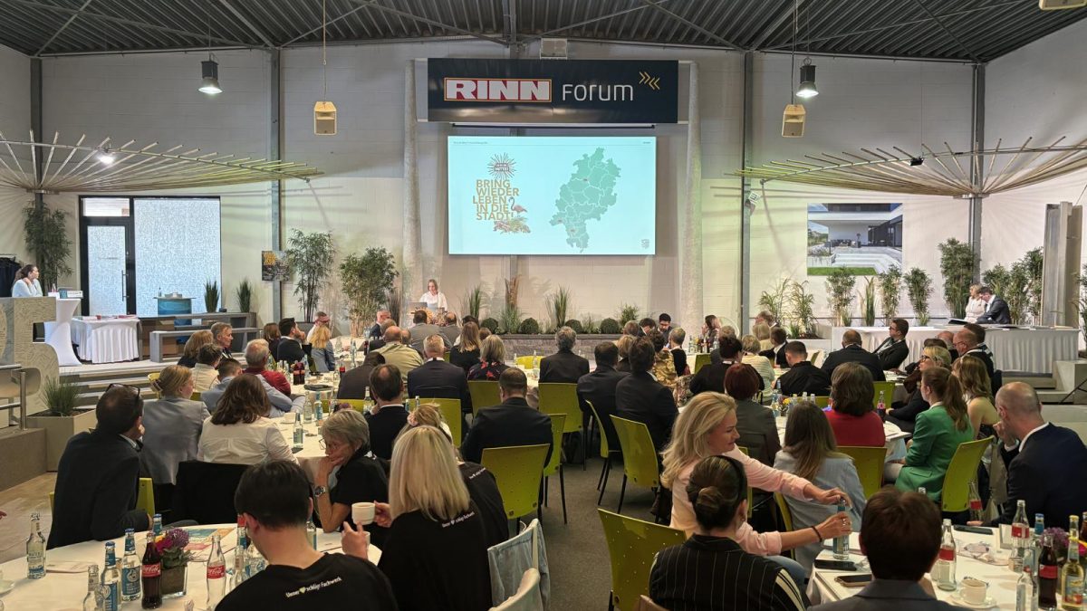 Stimmungsvolle Atmosphäre im RINN Forum: Die Preisverleihung von „Ab in die Mitte! 2026“ versammelte zahlreiche Gäste aus Politik, Kommunen und Wirtschaft rund um Bühne und Tischgruppen.