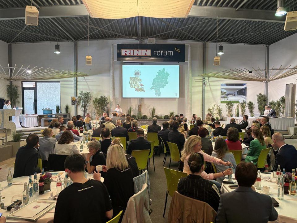 Stimmungsvolle Atmosphäre im RINN Forum: Die Preisverleihung von „Ab in die Mitte! 2026“ versammelte zahlreiche Gäste aus Politik, Kommunen und Wirtschaft rund um Bühne und Tischgruppen.