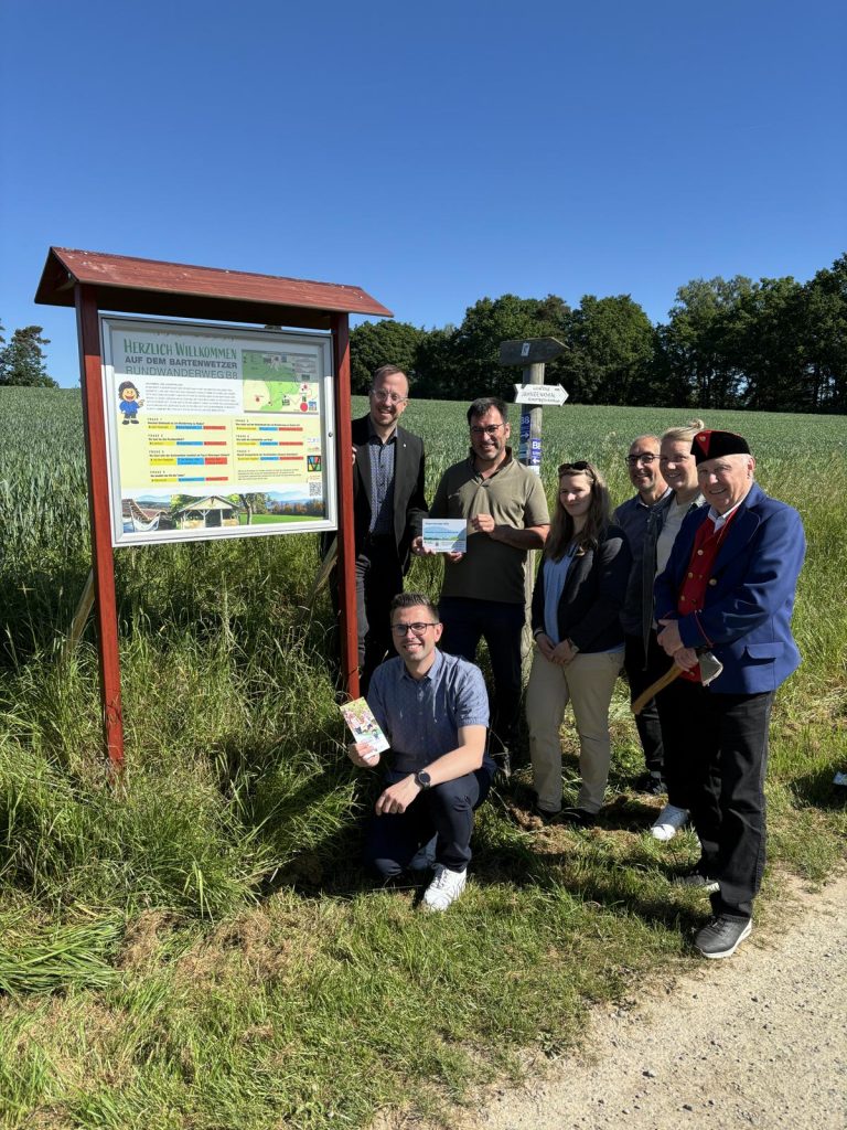 Gemeinsam am Schaukasten der Bartenwetzer-Rätseltour (von links): Bürgermeister Timo Riedemann, Alexander Dupont (Teamleiter Stadtentwicklung und Stadtmarketing der Stadt Melsungen), Christian Vieth (Regionalmanager Förderregion Mittleres Fuldatal), Dr. Rebekka Schütte (Regionalmanagerin Förderregion Mittleres Fuldatal), Hans-Werner Horn und Milena Bernhardt (Druckerei Horn) sowie die Bartenwetzer-Symbolfigur Manfred Schwarz. Die Beteiligten überzeugten sich vor Ort von der gelungenen Verbindung aus Heimatgeschichte, Wandern und interaktivem Lernen.